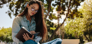 Student reading a book outdoors